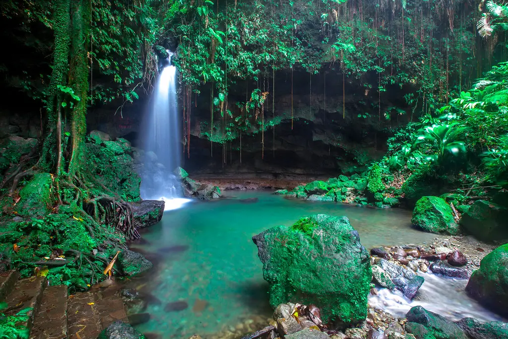 Waterfall and green swimming pool surrounded by rainforest at Emerald Pool, Dominica